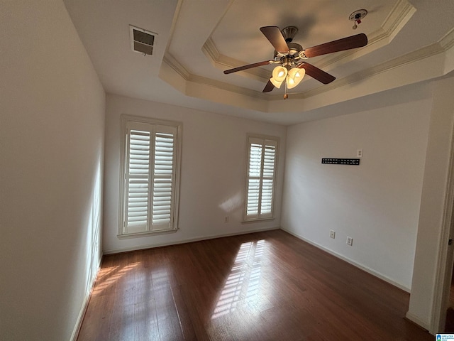 spare room with ceiling fan, ornamental molding, dark hardwood / wood-style flooring, and a tray ceiling