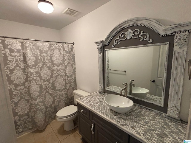 bathroom with toilet, vanity, and tile patterned floors