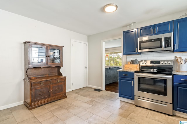 kitchen with decorative backsplash, blue cabinets, stainless steel appliances, and light stone counters