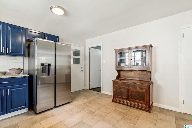 kitchen with blue cabinets, stainless steel refrigerator with ice dispenser, and tasteful backsplash