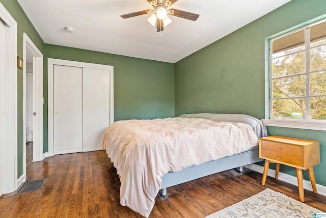 bedroom featuring dark wood-type flooring, a closet, and ceiling fan