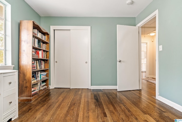 unfurnished bedroom featuring dark wood-type flooring and a closet