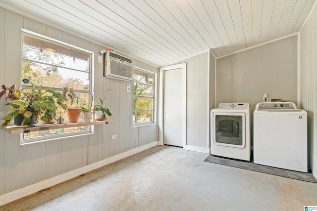 washroom with a wall unit AC, a healthy amount of sunlight, and washer and clothes dryer