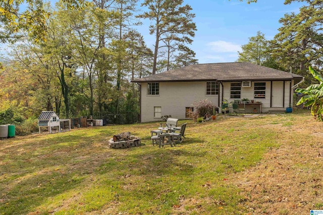 back of house with a yard, a shed, and a fire pit