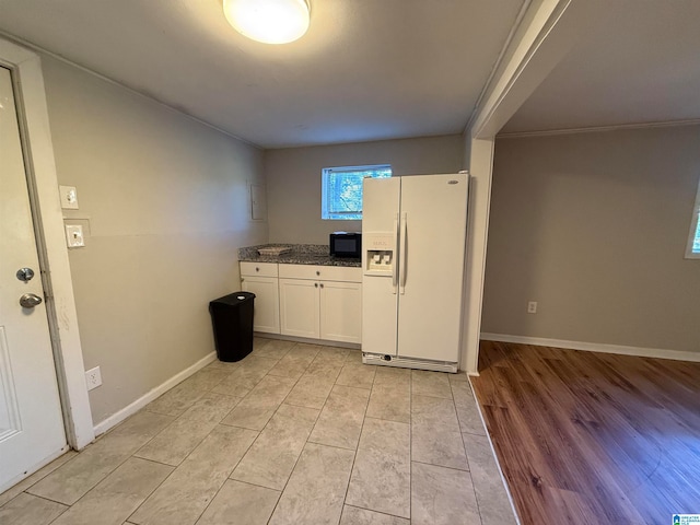 kitchen featuring crown molding, white cabinetry, white refrigerator with ice dispenser, and light wood-type flooring