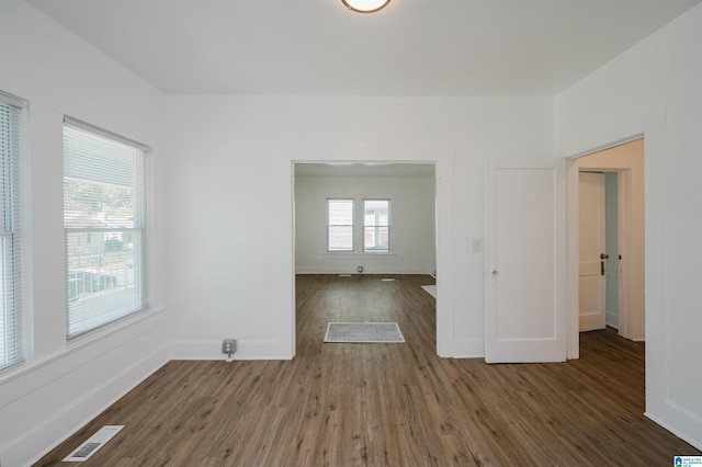 unfurnished room featuring a healthy amount of sunlight and dark hardwood / wood-style flooring