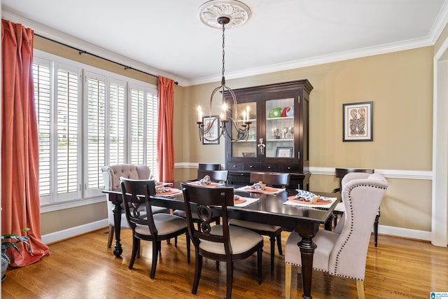 dining room featuring an inviting chandelier, crown molding, and light wood-type flooring