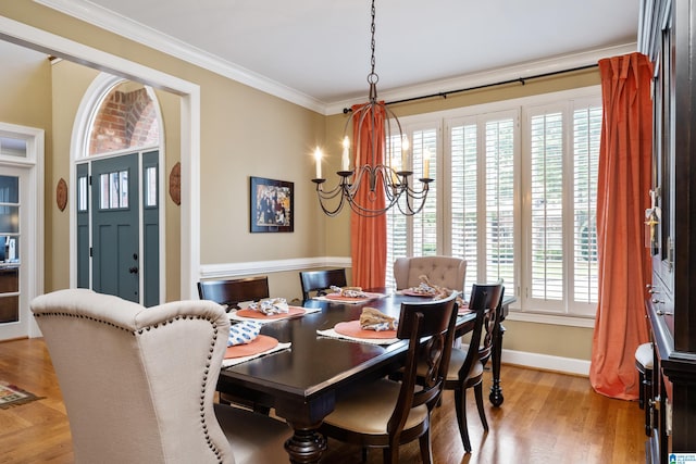 dining area featuring crown molding, light wood-type flooring, and an inviting chandelier