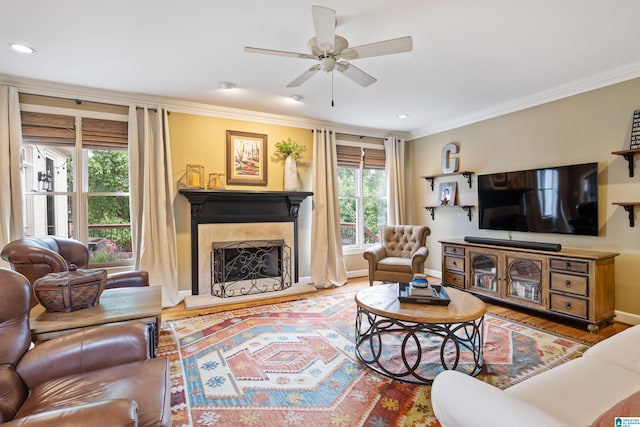 living room featuring ceiling fan, crown molding, wood-type flooring, and a high end fireplace