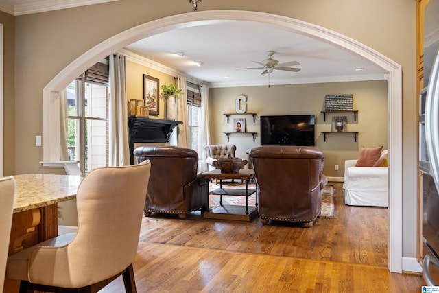 living room with ceiling fan, wood-type flooring, and ornamental molding