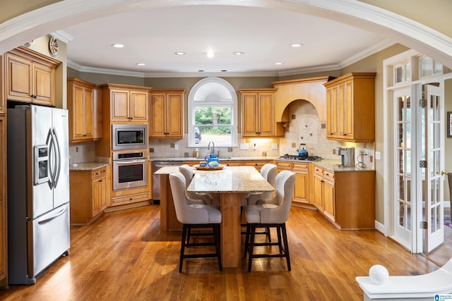 kitchen with light stone countertops, hardwood / wood-style flooring, appliances with stainless steel finishes, and a kitchen island