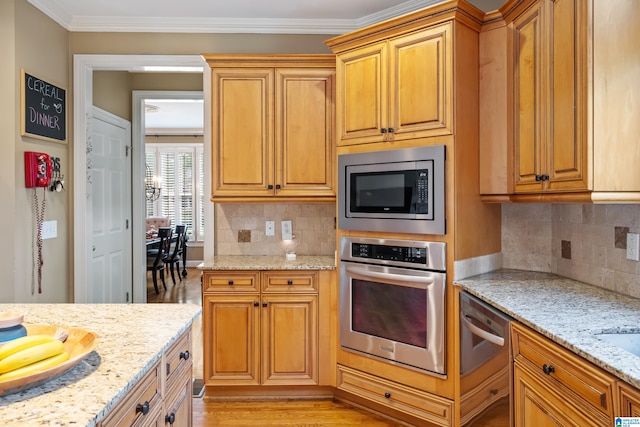 kitchen featuring light stone countertops, ornamental molding, appliances with stainless steel finishes, and light hardwood / wood-style floors