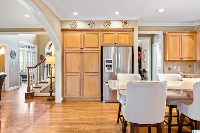 kitchen with decorative backsplash, stainless steel fridge, light stone countertops, light hardwood / wood-style flooring, and crown molding