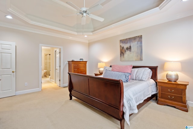 carpeted bedroom featuring crown molding, ensuite bath, a tray ceiling, and ceiling fan