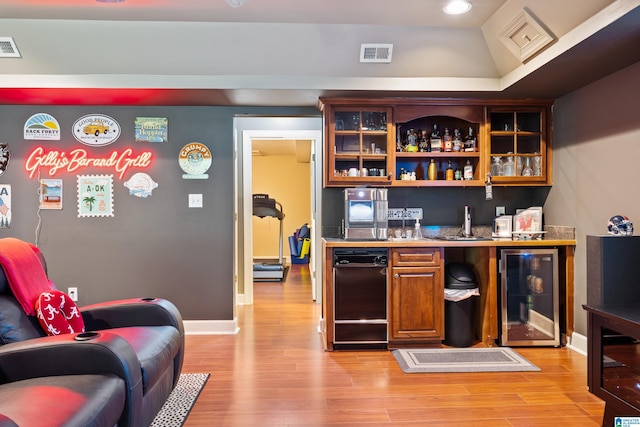 bar featuring wine cooler, vaulted ceiling, and light hardwood / wood-style floors