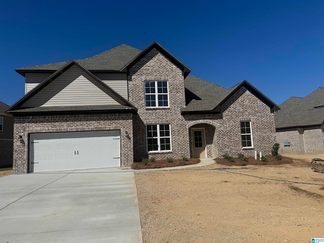 view of front of property with an attached garage, brick siding, and driveway