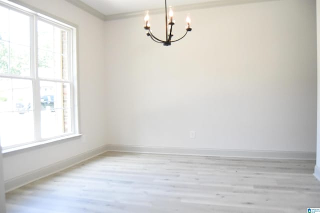 empty room with an inviting chandelier, crown molding, baseboards, and light wood-type flooring