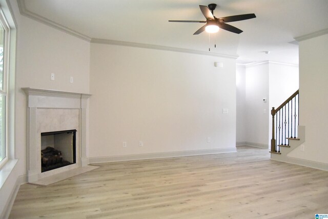 unfurnished living room with baseboards, a high end fireplace, ornamental molding, stairs, and light wood-style floors