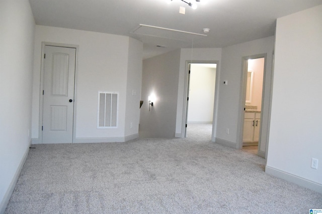 unfurnished bedroom with attic access, light colored carpet, visible vents, and baseboards