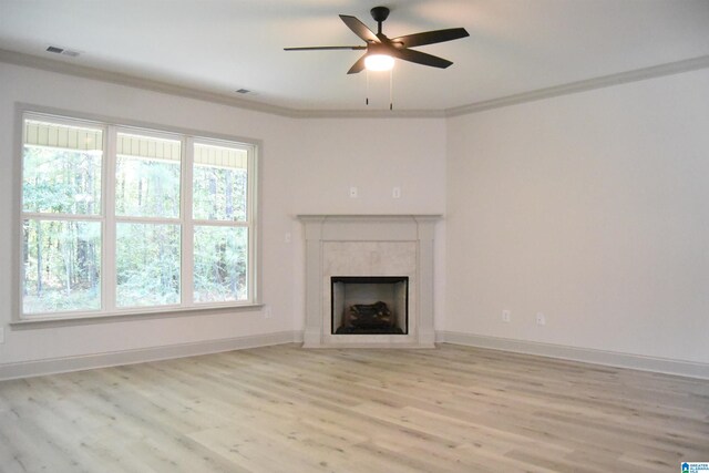 unfurnished living room with visible vents, ornamental molding, a high end fireplace, light wood-style floors, and baseboards