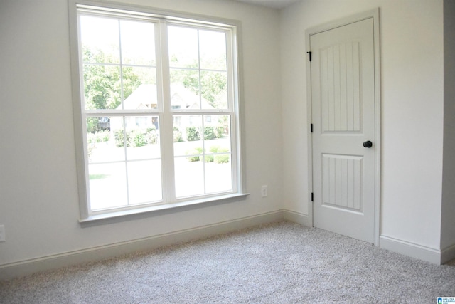 carpeted spare room featuring a healthy amount of sunlight and baseboards