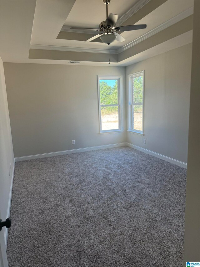 carpeted spare room featuring a ceiling fan, baseboards, visible vents, crown molding, and a raised ceiling