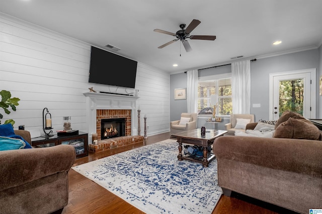 living room with dark wood-type flooring, a brick fireplace, a healthy amount of sunlight, and ceiling fan