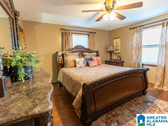 bedroom with dark hardwood / wood-style floors, a textured ceiling, and ceiling fan