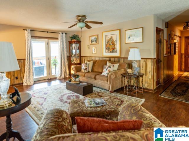 living room with ceiling fan, wood walls, and dark hardwood / wood-style floors