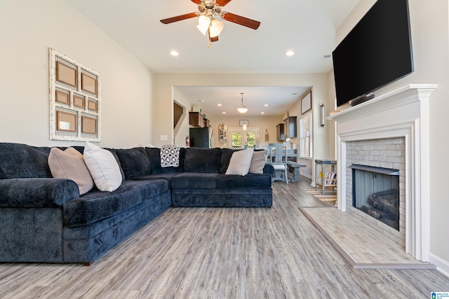 living room with wood-type flooring, a fireplace, and ceiling fan