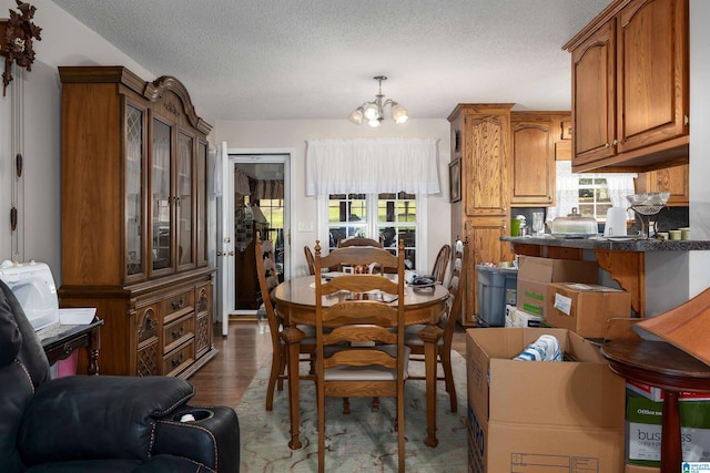 dining space with light hardwood / wood-style flooring, a textured ceiling, and an inviting chandelier