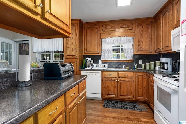 kitchen featuring white appliances, backsplash, wood-type flooring, and sink