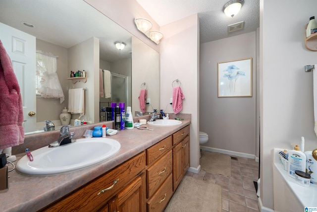 bathroom featuring a textured ceiling, toilet, vanity, an enclosed shower, and tile patterned flooring