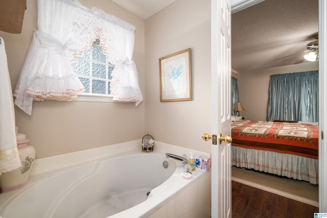 bathroom with a bath, ceiling fan, a textured ceiling, and wood-type flooring