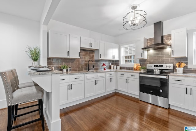 kitchen with white cabinetry, wall chimney exhaust hood, stainless steel electric range, and decorative light fixtures