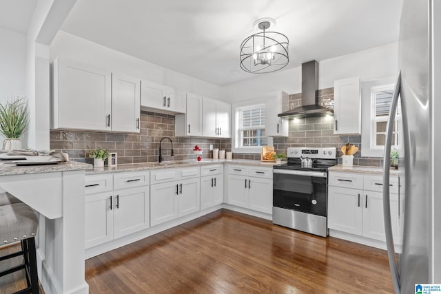 kitchen with white cabinets, sink, pendant lighting, wall chimney exhaust hood, and stainless steel appliances