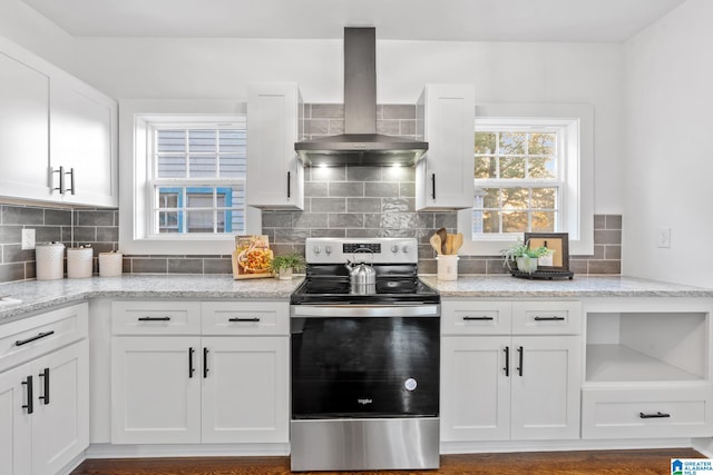 kitchen with stainless steel range with electric cooktop, wall chimney exhaust hood, white cabinets, light stone counters, and hardwood / wood-style flooring