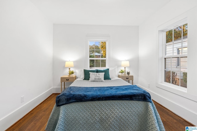 bedroom with multiple windows and dark hardwood / wood-style flooring