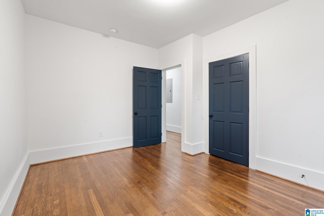 empty room featuring electric panel and wood-type flooring