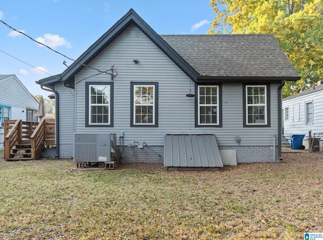 rear view of property with a yard and central air condition unit