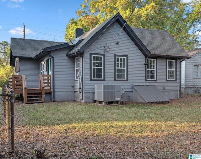 rear view of property with central air condition unit, a deck, and a yard