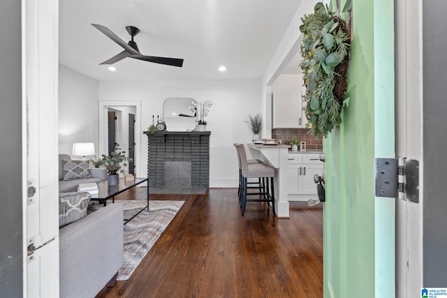 interior space with ceiling fan, dark hardwood / wood-style flooring, and a fireplace