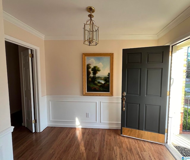 foyer entrance with ornamental molding, a notable chandelier, and dark hardwood / wood-style floors