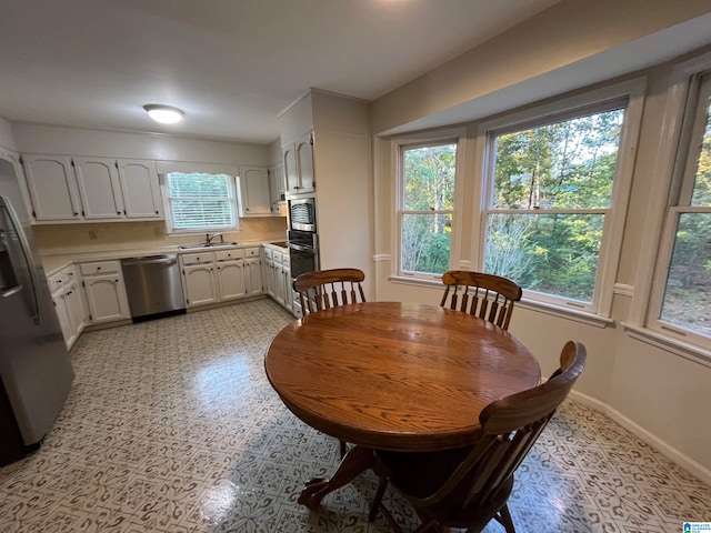 dining area with sink, light tile patterned flooring, and a wealth of natural light