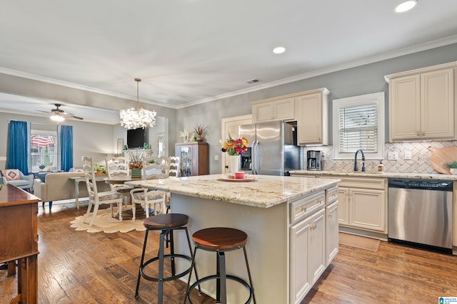 kitchen featuring stainless steel appliances, ceiling fan with notable chandelier, decorative light fixtures, light hardwood / wood-style flooring, and a kitchen island