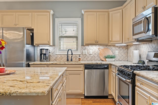 kitchen featuring backsplash, appliances with stainless steel finishes, light stone counters, and cream cabinetry