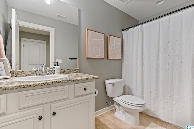 bathroom with toilet, vanity, and tile patterned floors