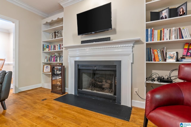 living room featuring light hardwood / wood-style floors, ornamental molding, and built in shelves