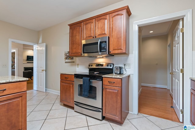 kitchen with stainless steel appliances, light stone countertops, light tile patterned flooring, and tasteful backsplash