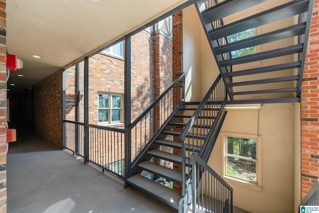 stairway with a towering ceiling, concrete floors, and brick wall